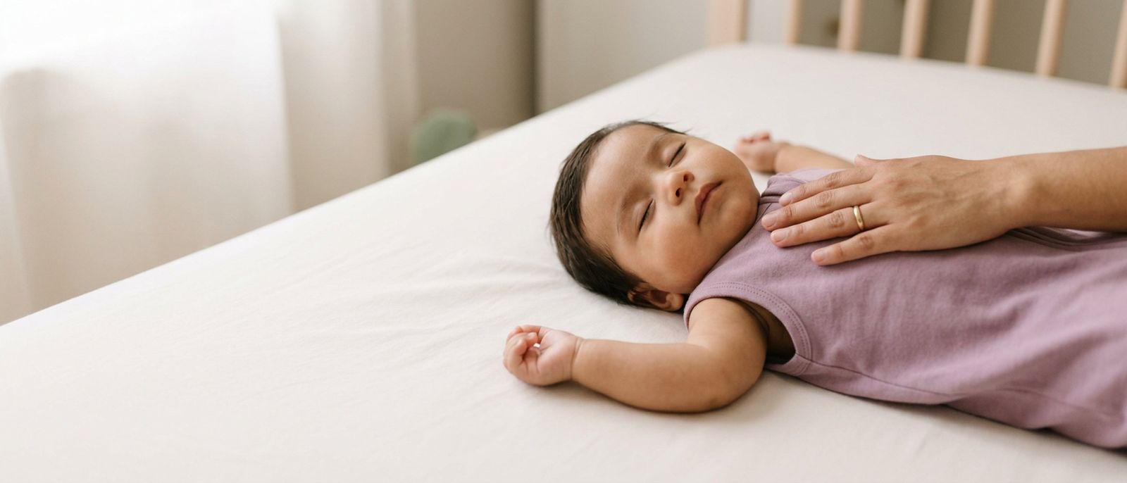 Mamá con la mano sobre el pecho de su bebé, que duerme boca arriba